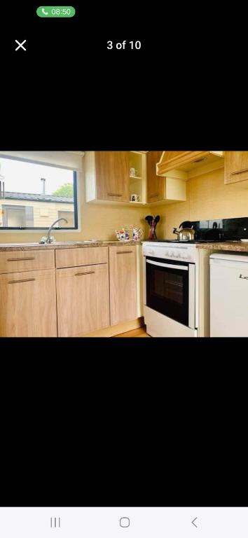 a kitchen with wooden cabinets and a white stove top oven at Caravan 63 Fishguard Holiday Park in Fishguard