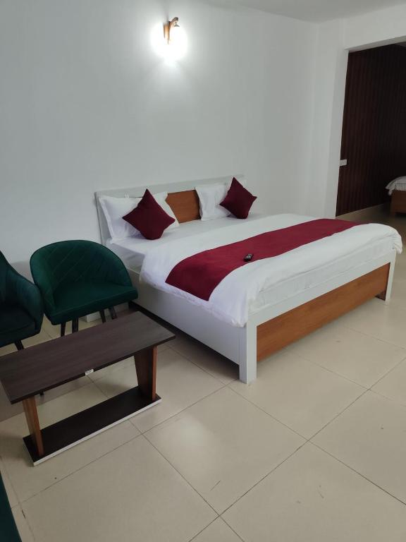 a bedroom with a bed and a green chair at Vybent hotel kainchi dham in Bhowāli