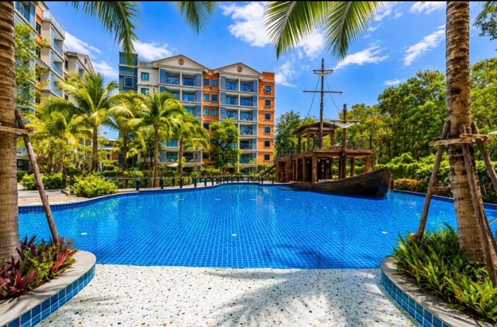 a swimming pool at a resort with palm trees at The Title Residencies Naiyang in Phuket