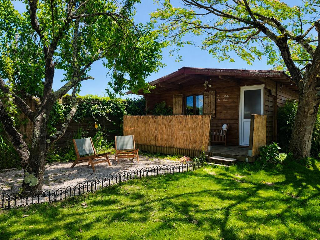 a backyard with two chairs and a house at Le Chalet des Pins - La Forge De Clermont in Clermont
