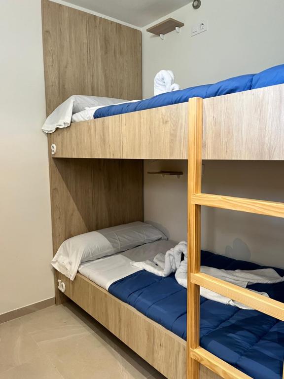 a room with bunk beds with blue sheets and a ladder at Albergue Hostel Barosa in Barro