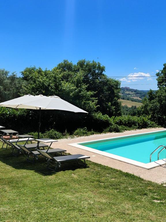 a swimming pool with an umbrella and lounge chairs next to it at sacrobosco Country House in Porchiano