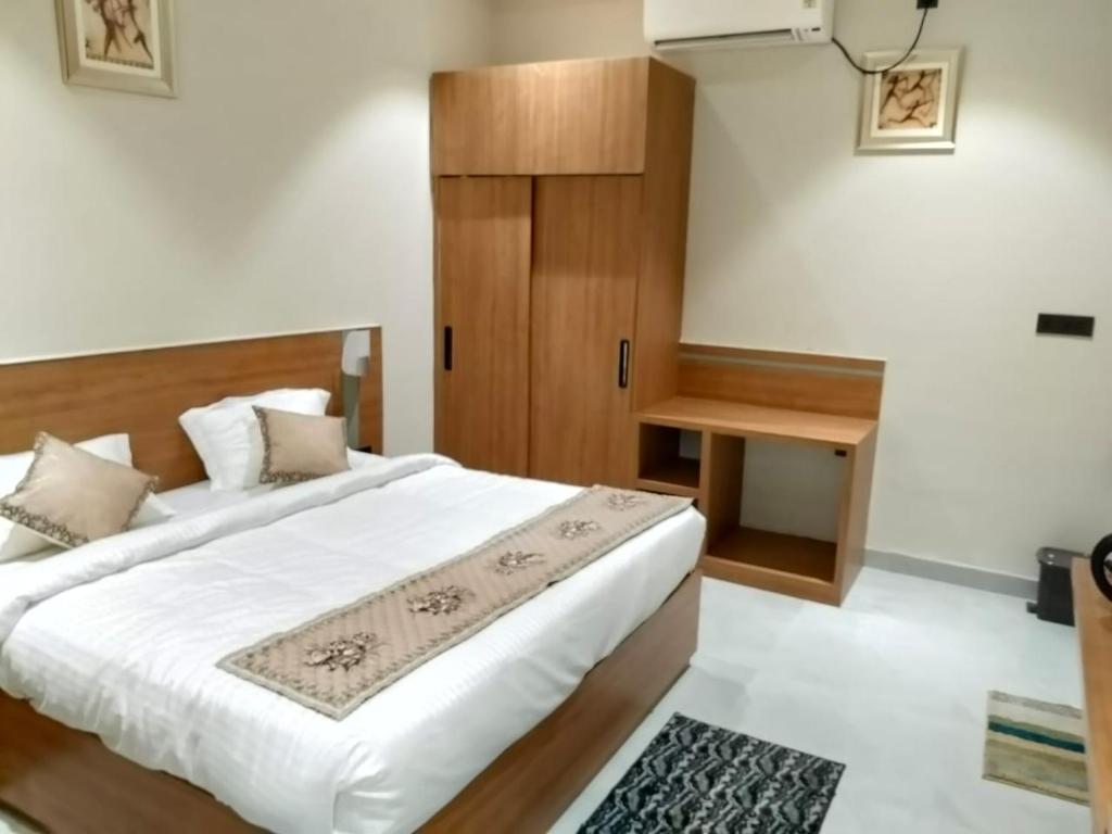 a bedroom with a large white bed and a wooden cabinet at Yash Residency in Bharāwās