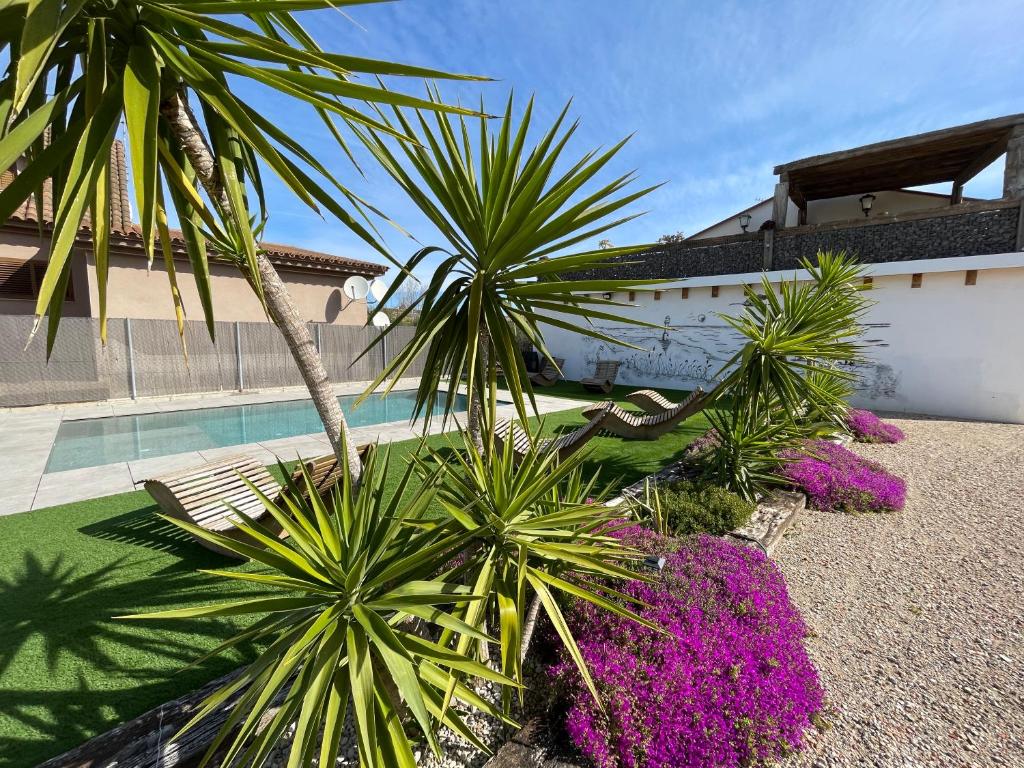 a group of palm trees and purple plants in front of a building at Casa Rural MESTRE in Deltebre