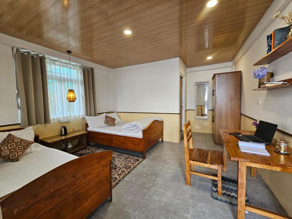 a room with two beds and a desk with a laptop at Kotheybari homestay in Pakhyong