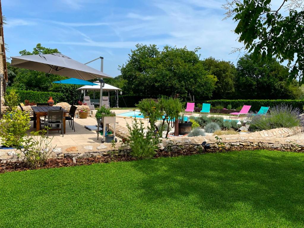 a backyard with a pool with a table and an umbrella at Maison M in Surin