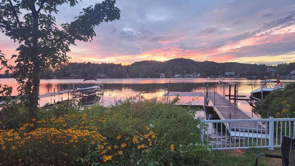 a dock with boats on a lake at sunset at Chalet Ohana in Adstock