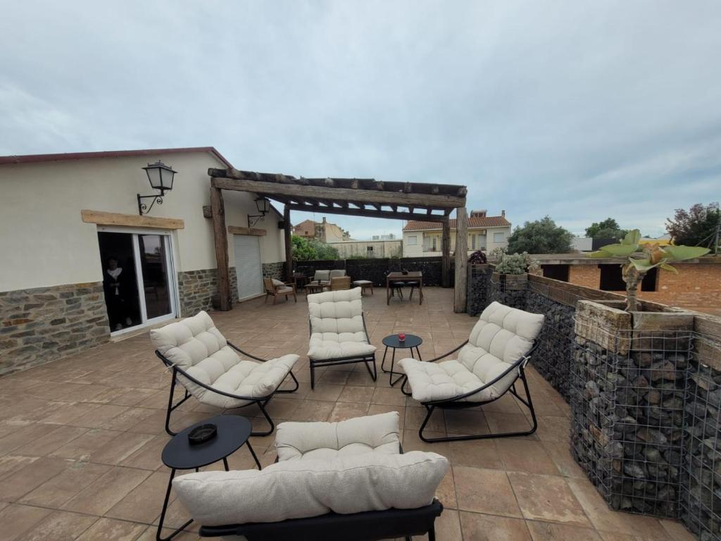 a patio with white chairs and a stone wall at Casa rural Maño in Deltebre