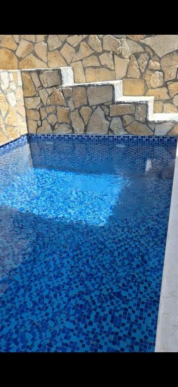a swimming pool with blue water and a stone wall at White Apartman in Dobra Voda