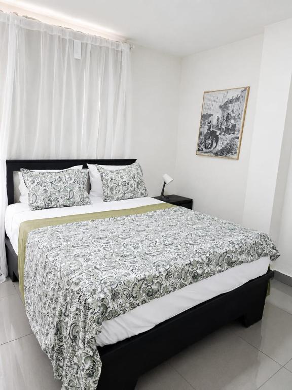 a bedroom with a bed with a black and white comforter at Hostal Santa Barbara in Santo Domingo