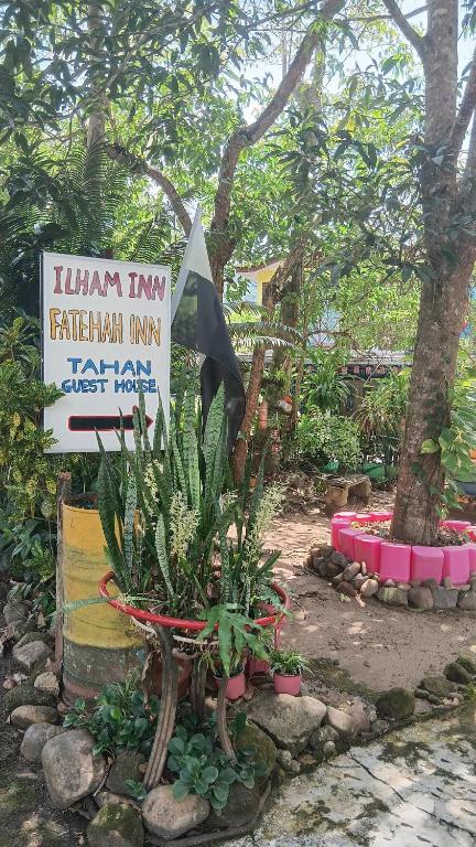 a sign in a garden with some plants and trees at Ilham inn in Jerantut