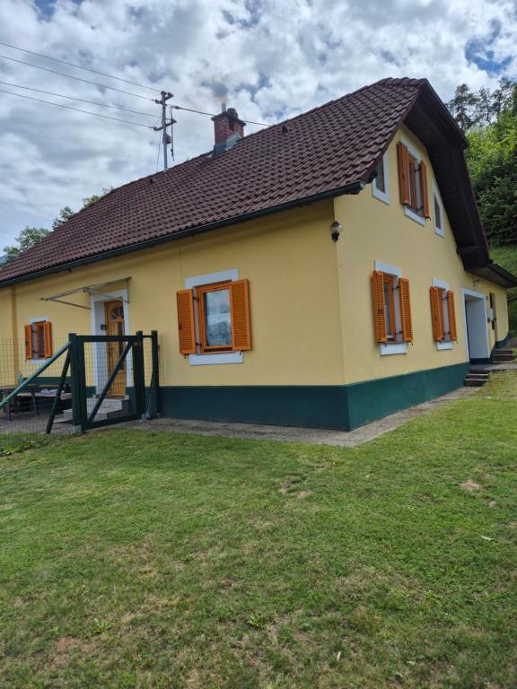 a yellow house with brown windows and a yard at Chalet an der Sonne nahe Klopeiner See und Petzen Bergbahn in Sankt Stefan