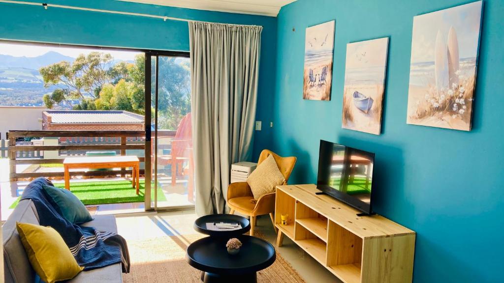 a living room with a tv and a blue wall at Luxury Smart Studio - Sea and Mountain Views - Gordon's Bay in Gordonʼs Bay