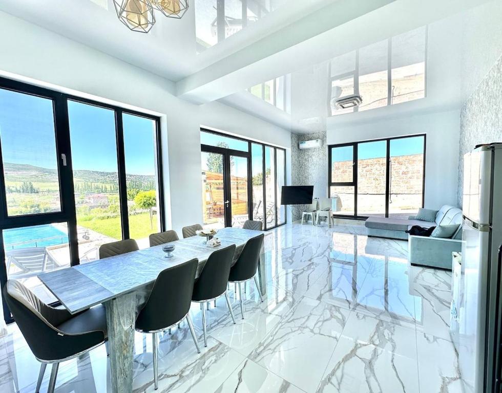 ein Esszimmer mit Tisch, Stühlen und Fenstern in der Unterkunft White Location in Dzoraghpʼyur