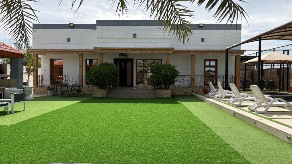 a house with chairs and a lawn in front of it at AlZaeem Resort & Hotels in Barka