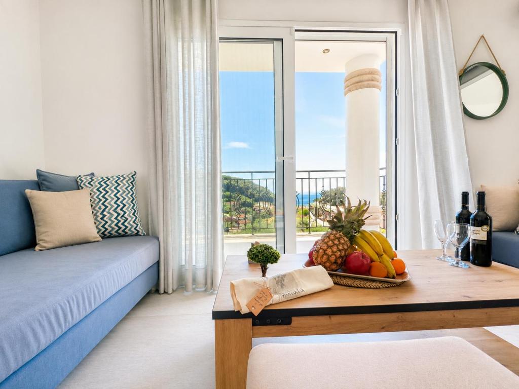 a living room with a blue couch and a table with fruit at Natura Luxury Suites Parga in Parga
