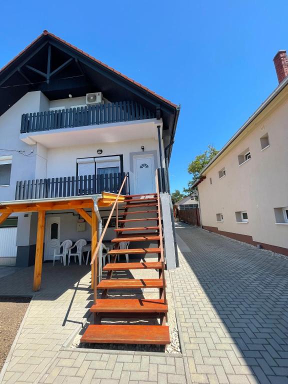a house with wooden stairs leading up to a building at Fefe Apartman in Balatonlelle