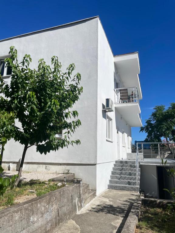 a white building with stairs next to a tree at Mariyka Apartaments 2 in Sutomore