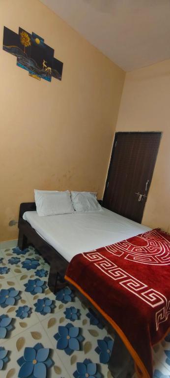 a bedroom with a bed with a red blanket on it at Radhe House in Dwarka
