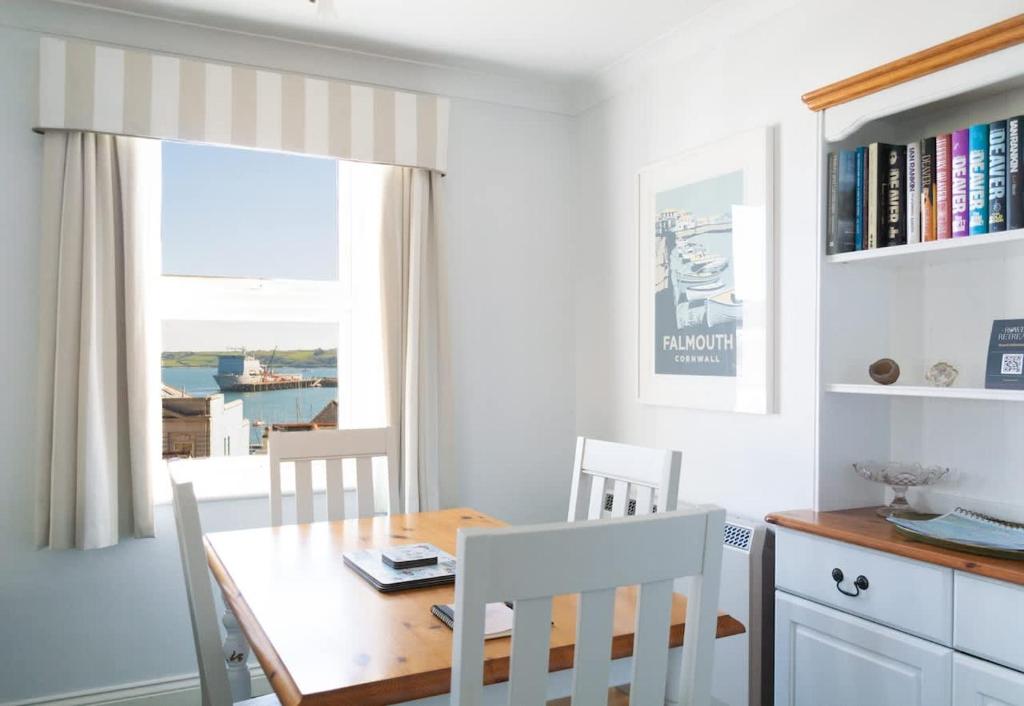 a dining room with a table and chairs and a window at Eagles Nest - By Rowes Retreats in Falmouth