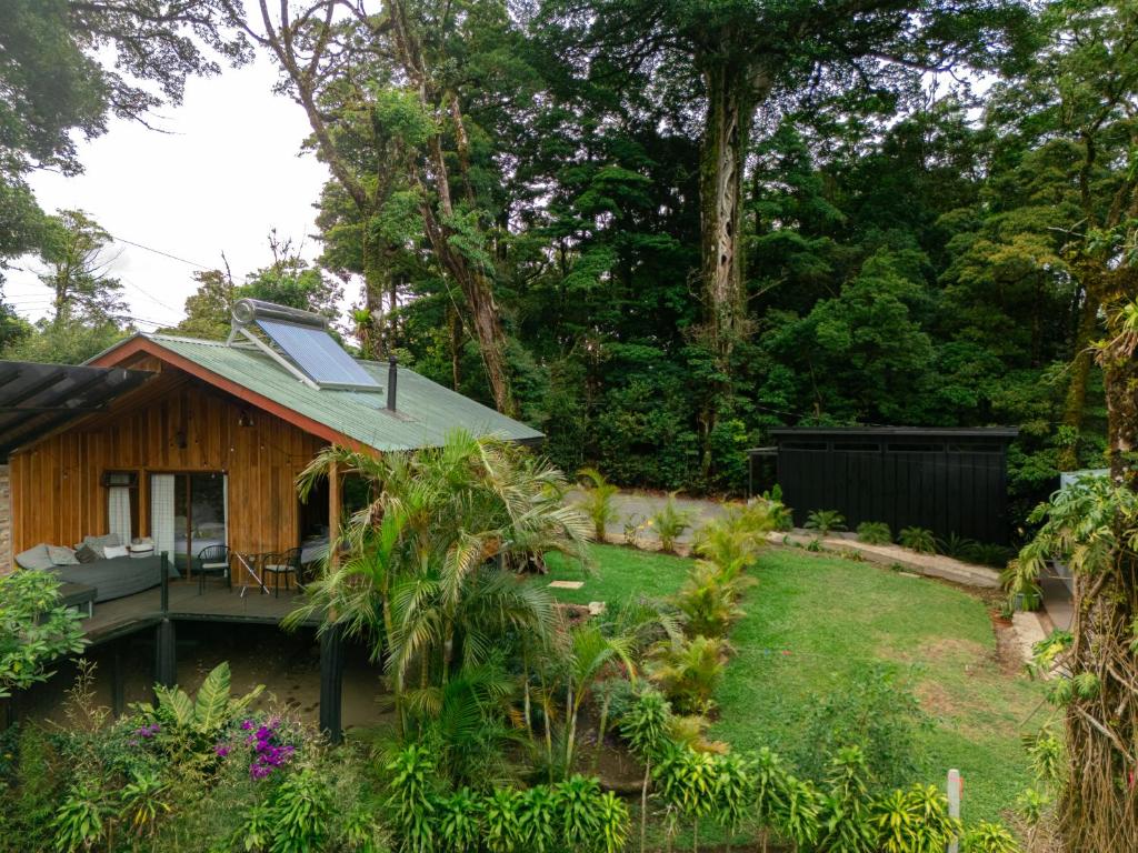 a garden with a small wooden house with a yard at Cabañas Hoja Verde in Monteverde Costa Rica
