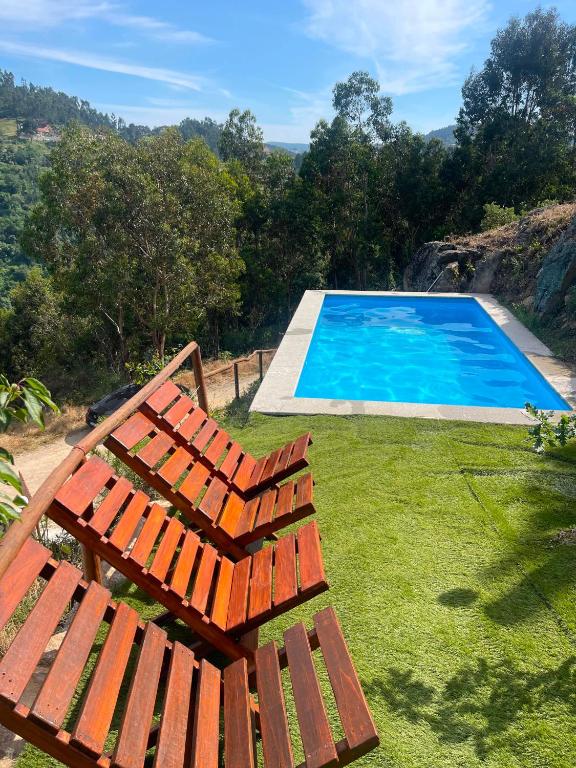 a view of a swimming pool and two wooden chairs at Pedra Douro in Fontelas