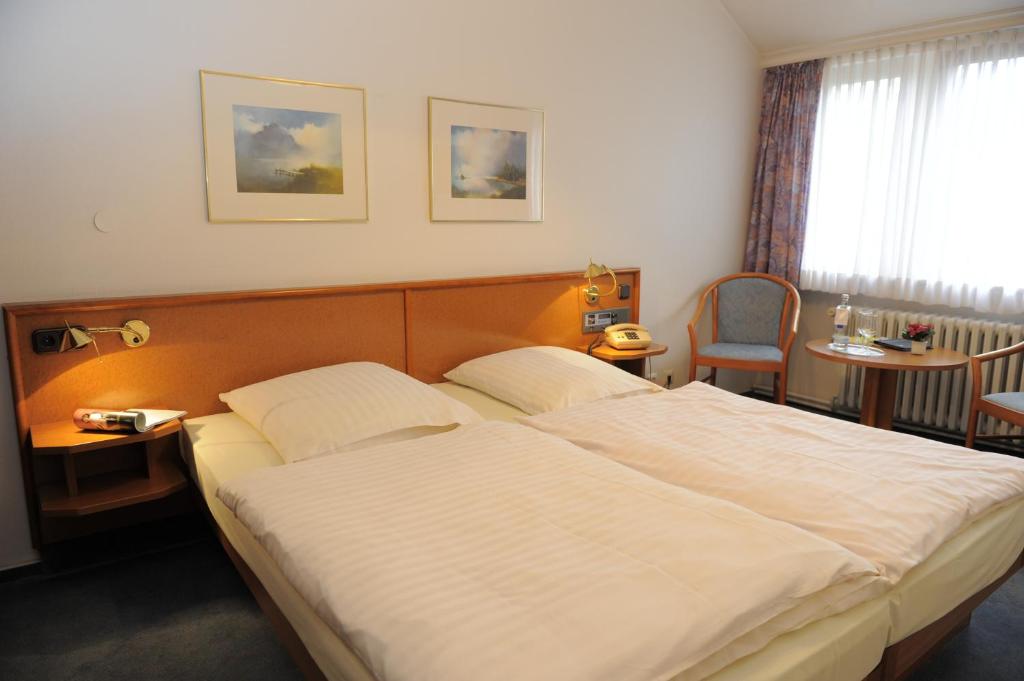 ein Schlafzimmer mit einem großen weißen Bett und einem Stuhl in der Unterkunft Hotel Heldt in Bremen