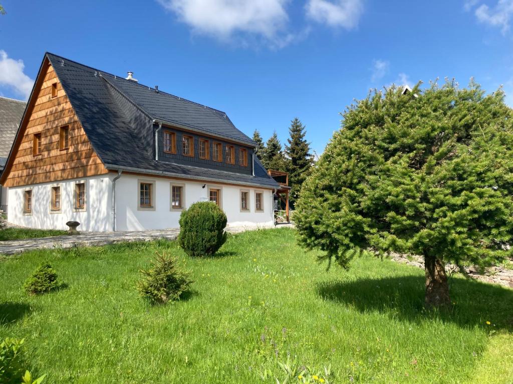 a white house with a black roof and a tree at Ferienhaus Zirbenliebe Altenberg in Kurort Altenberg