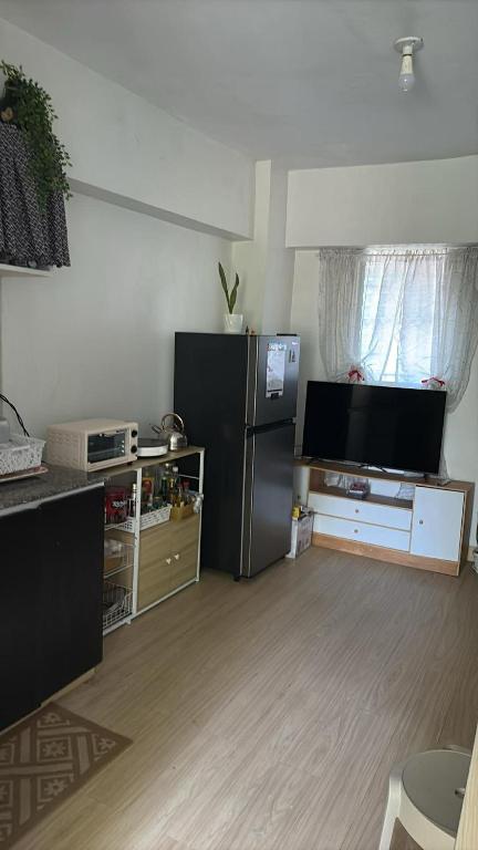 a living room with a refrigerator and a television at CJ's Travellers Room in Maribago