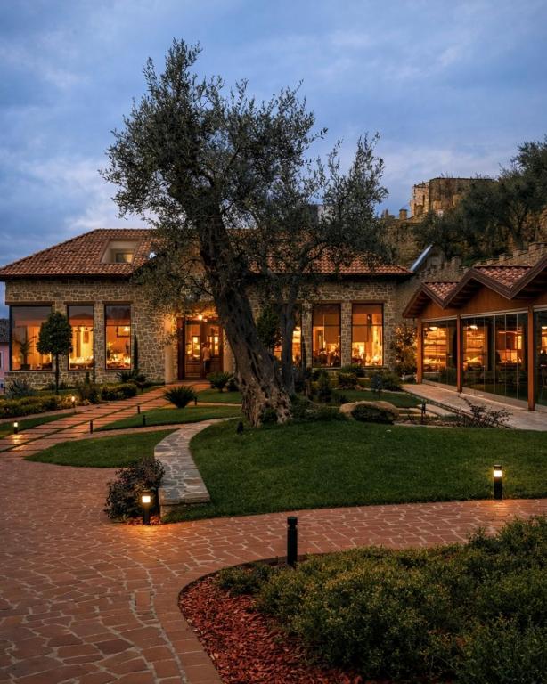 a large house with a tree in front of it at Hotel Protino in Fushë-Prezë