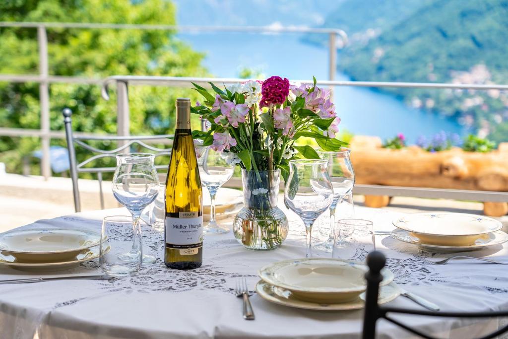 a table with a bottle of wine and a vase of flowers at Incanto del Lago Country House in Faggeto Lario 
