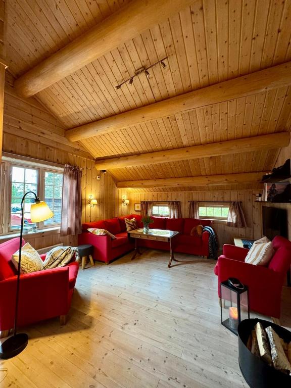 a living room with red couches and a wooden ceiling at Cabin in Tuddal in Hjartdal