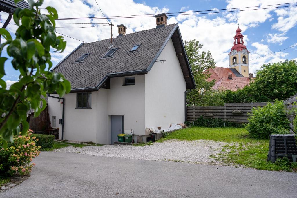a white house with a church in the background at Apartma BONUS in Begunje na Gorenjskem