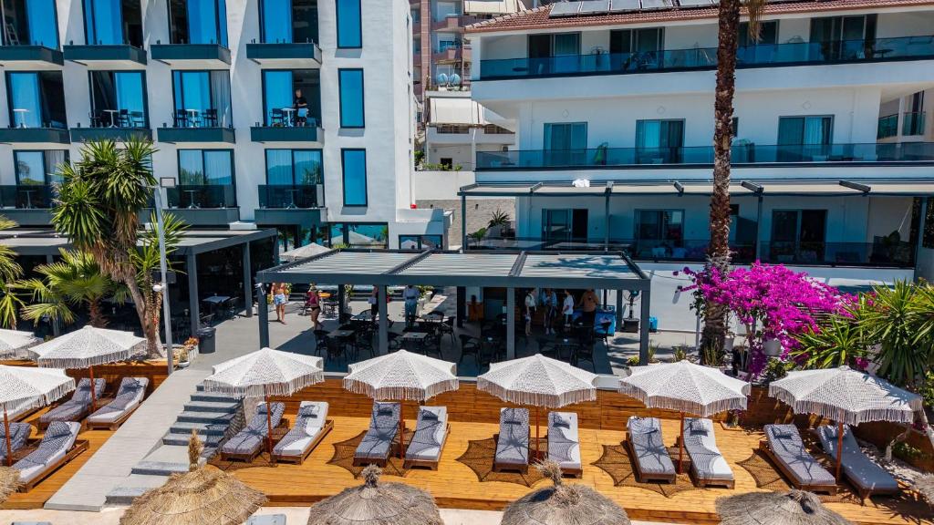 an outdoor patio with chairs and umbrellas and a building at Vila Era Beach 2 in Sarandë