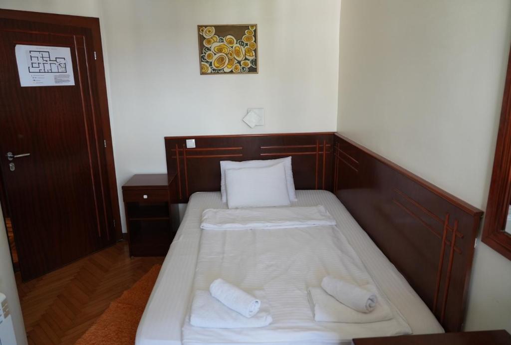 a small bedroom with two beds with white sheets at Konačište Compass in Kraljevo
