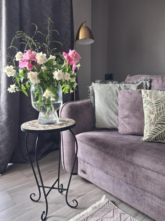 a vase of flowers on a table next to a couch at Few Steps to the Bay in Jūrmala