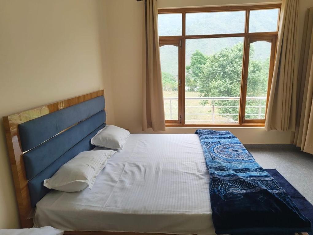 a bedroom with a bed with a large window at Hotel Aditya in Dharāsu