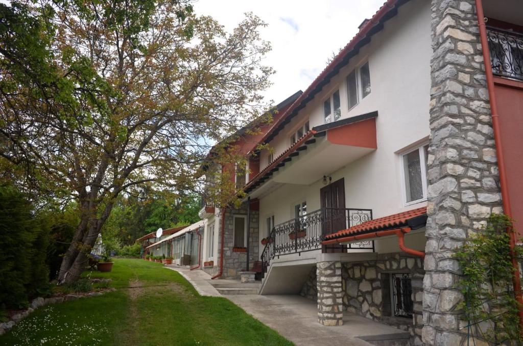 a white building with a yard next to a house at Casă de oaspeți autentică în Transilvania in Izvoru Mureşului