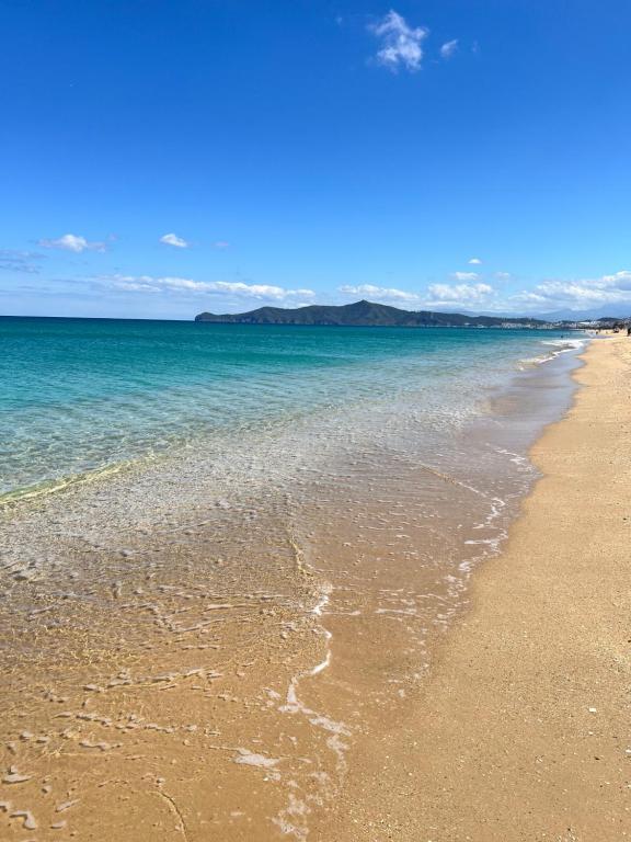 a sandy beach with the ocean and mountains in the background at Beachside Garden Apartment in Marina Smir in Marina Smir