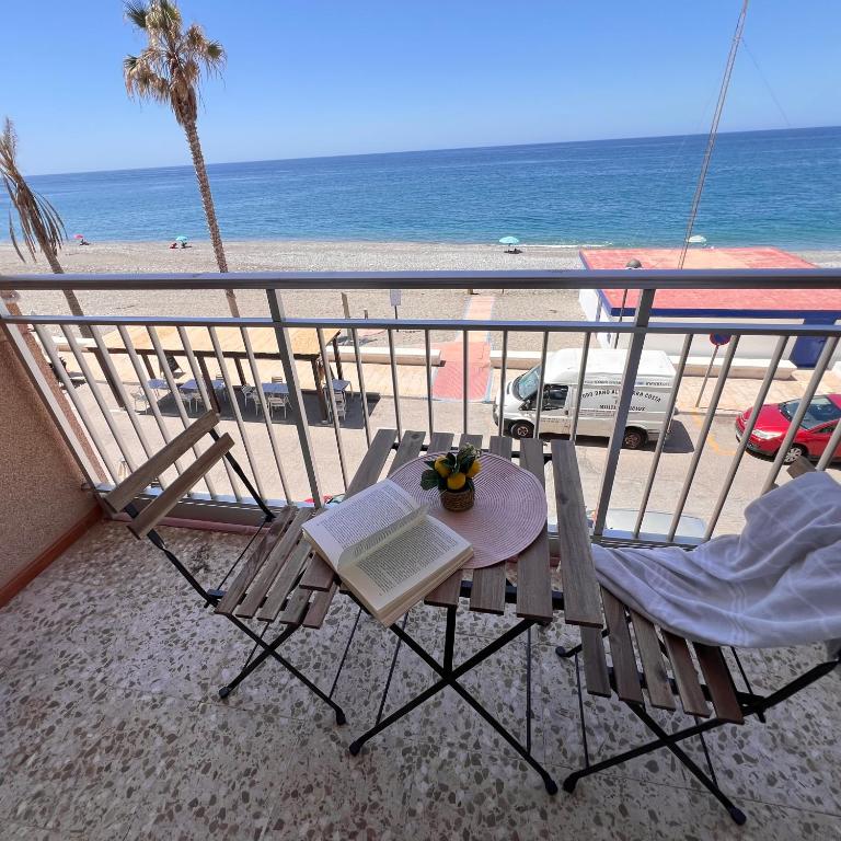 a balcony with a table and chairs and the beach at Todimer Acera del Mar in Torrenueva