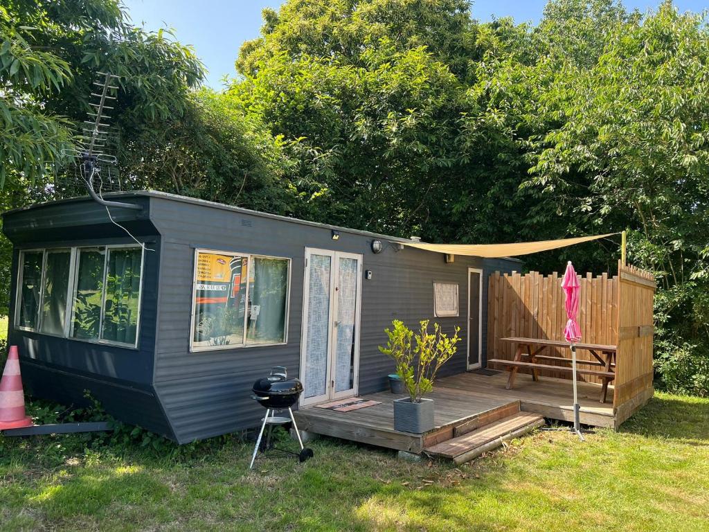 a tiny house with a porch and a grill at Gite "home" - piscine in Juvigny-le-Tertre