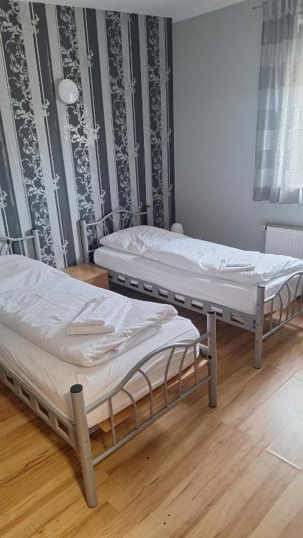 two twin beds in a room with wooden floors at Pension Alis Augsburg in Augsburg