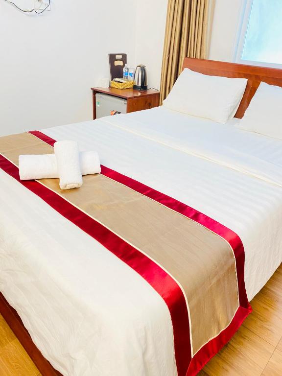 a bedroom with a large bed with red and white sheets at Minh Thư Phú Mỹ Hotel in Phú Mỹ