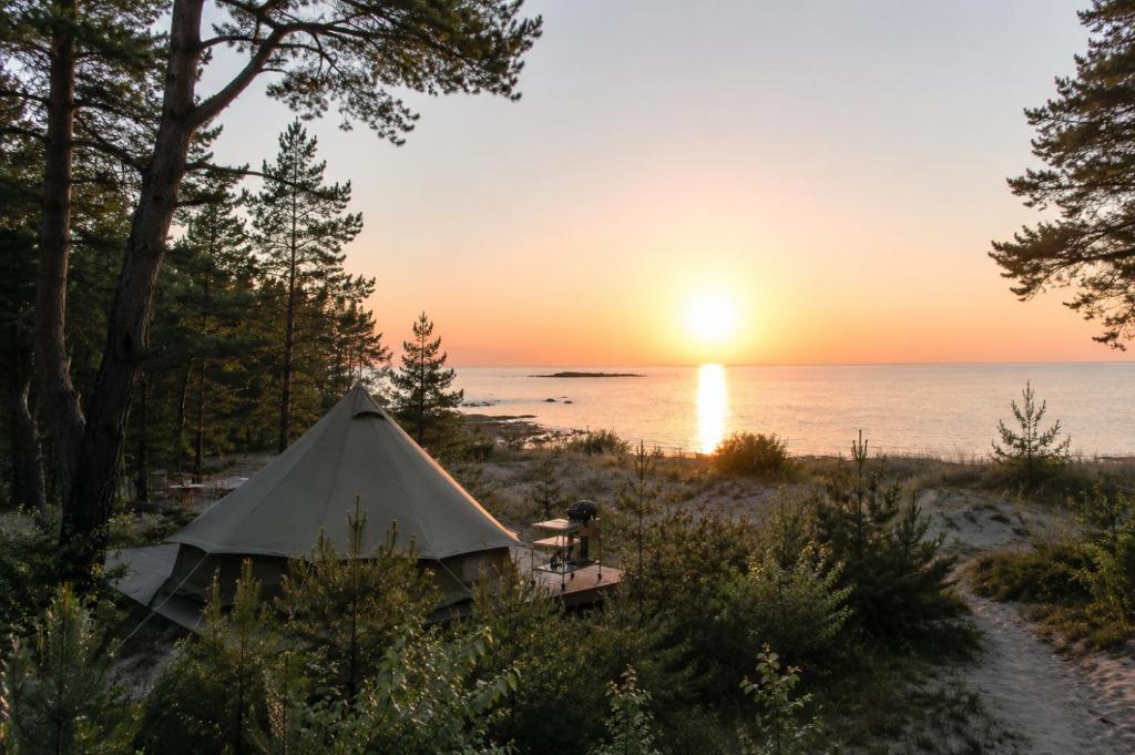 a tent on the beach with the sunset in the background at Gnista Glamping in Fäboda