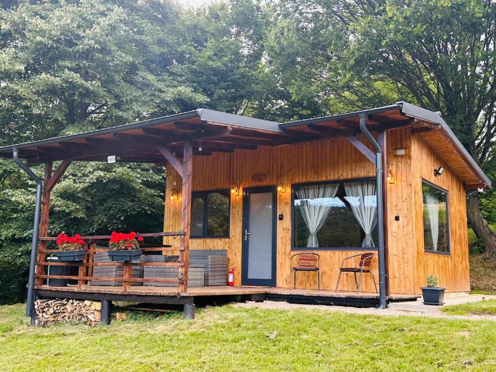 a tiny house with a porch and a roof at Wood Nest Curtea de Argeș - Cabană de vacanță în natură in Curtea de Argeş