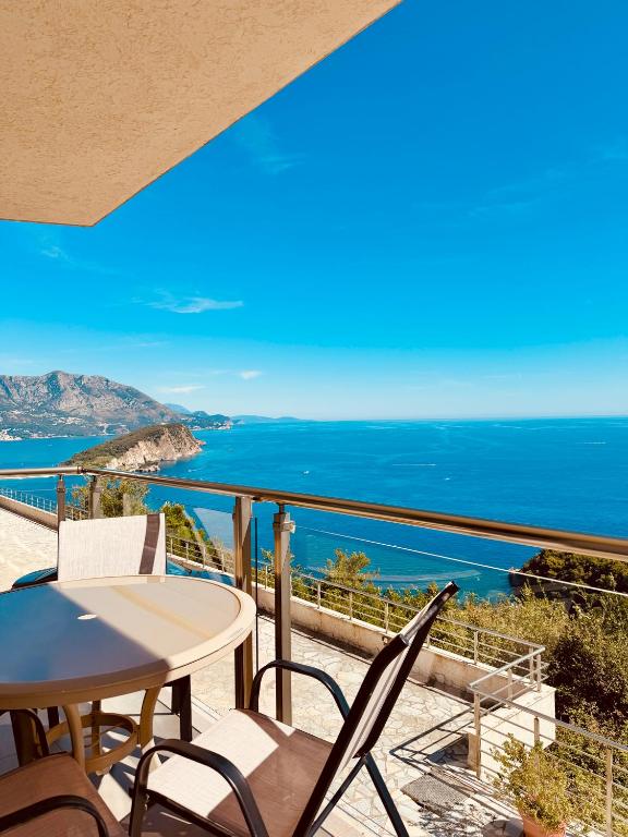 a balcony with a table and chairs and the ocean at Skyline View Apt & Sea View Terrace in Budva