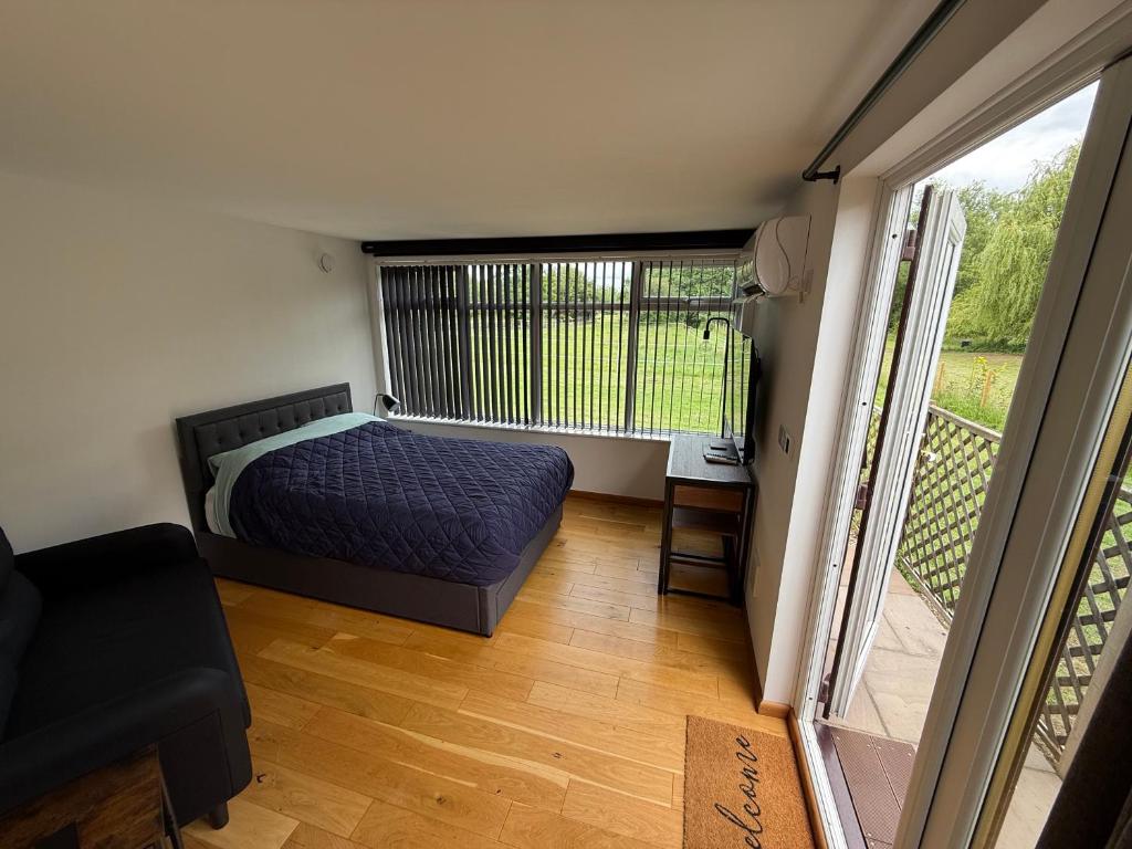 a bedroom with a bed and a balcony at Summerhouse in Honington