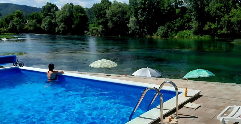 a person in a swimming pool next to a river at Apartmani na Uni Šarac in Otave