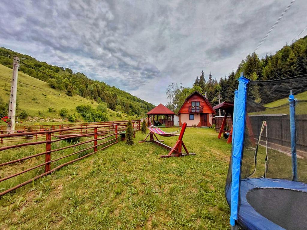 a playground in a field next to a fence at Cabana MARA in Poiana Vadului