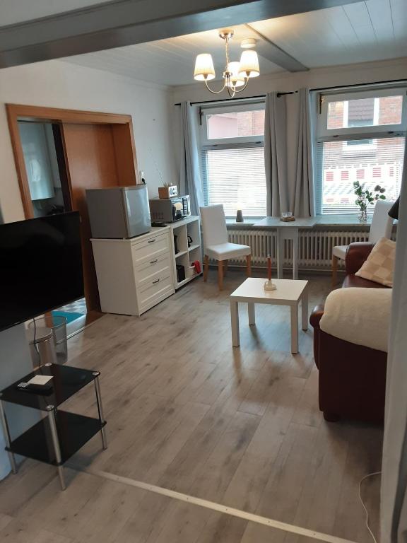 a living room with a couch and a tv and a table at Das weiße Stadthaus in Wesselburen